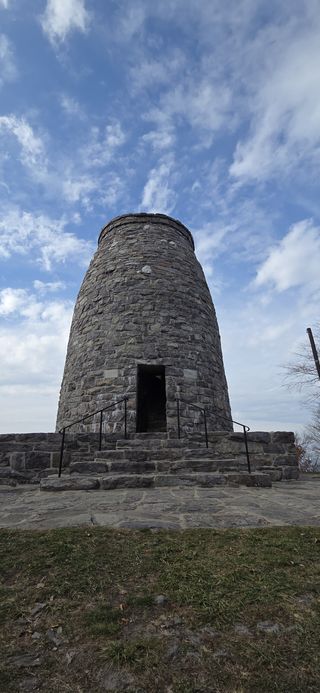 From below, a view of the gray stone monument with its iron front gate open for visitors.