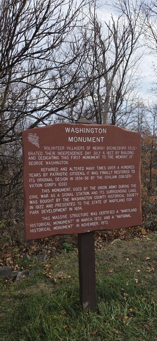 A red sign detailing the history of how this monument came to be and everything it's been through since.